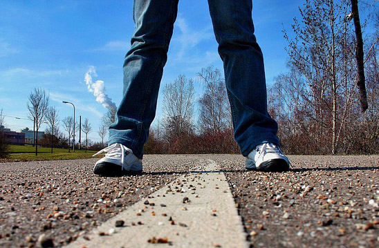 2 benen (spijkerbroek, witte sneakers) midden op de weg