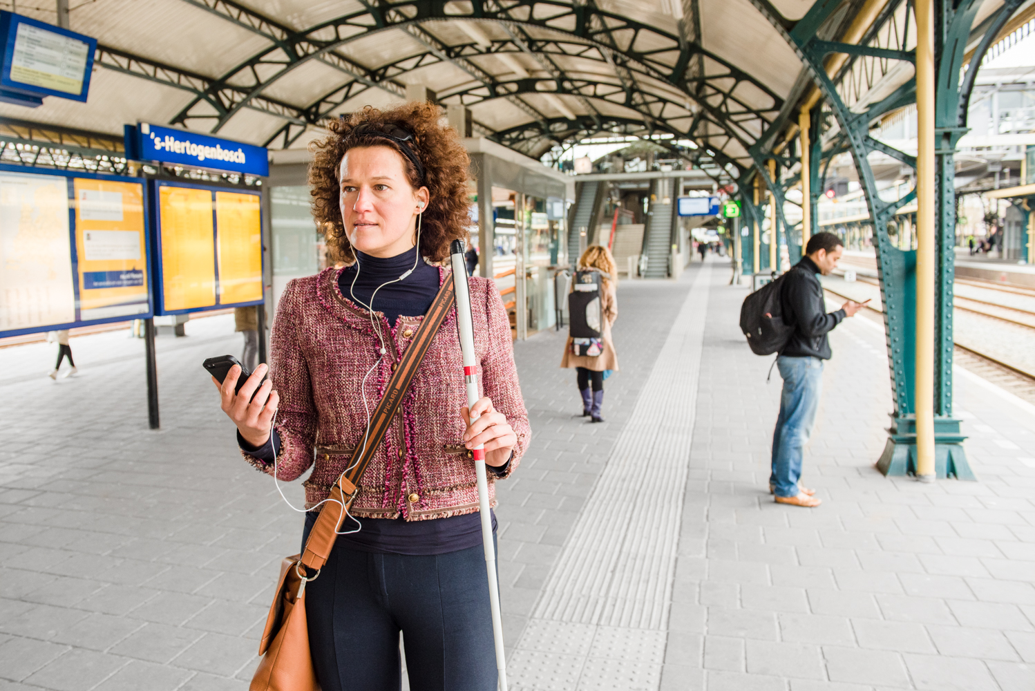 Slechtziende vrouw kijkt naar haar smartphone op het station