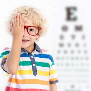 Kind met hand voor zijn oog naast een wazige letterkaart