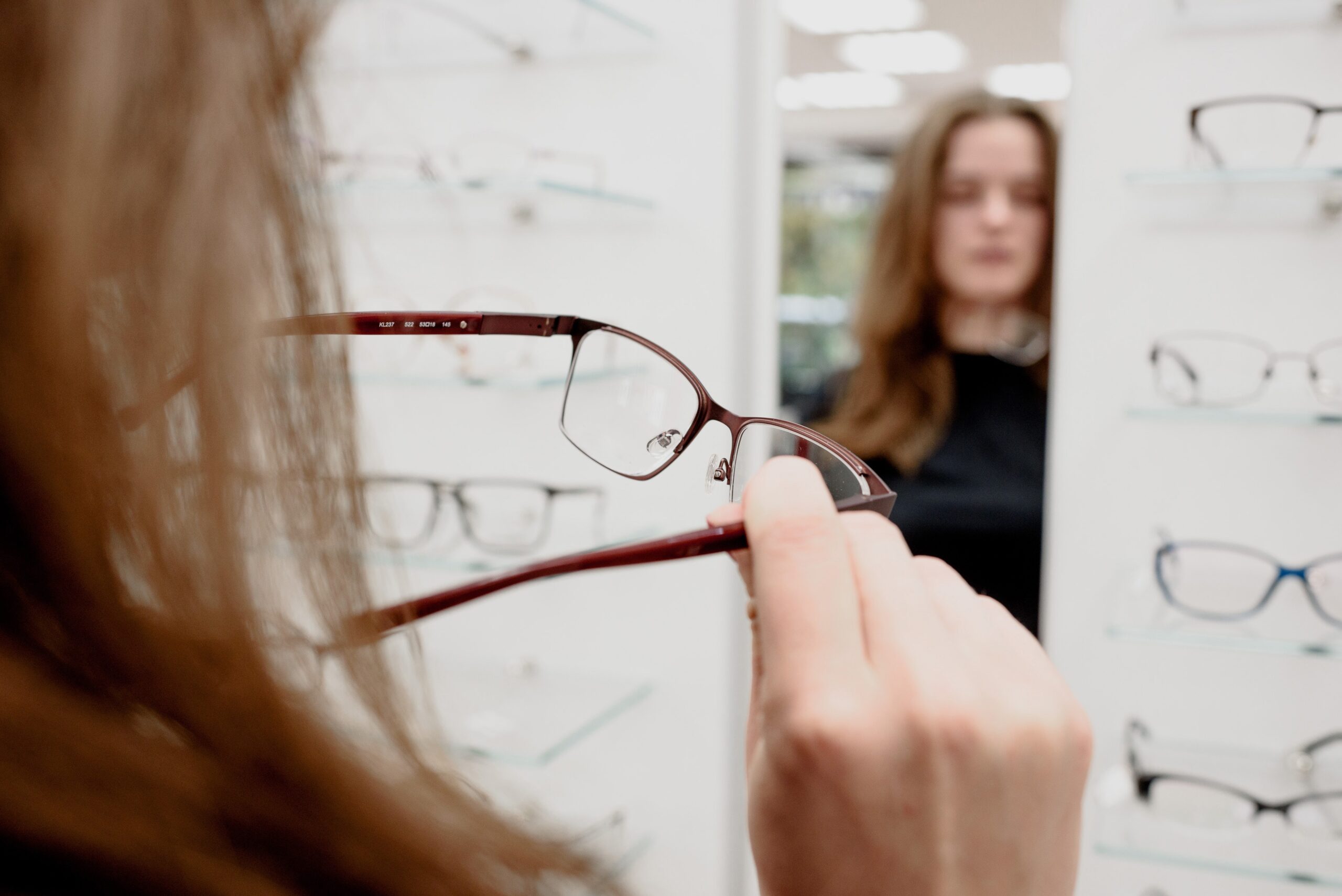 Bijziende vrouw kijkt bij de opticien in de spiegel
