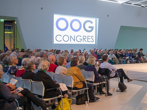 Zaal vol mensen met aan de wand een scherm met het logo van het Oogcongres