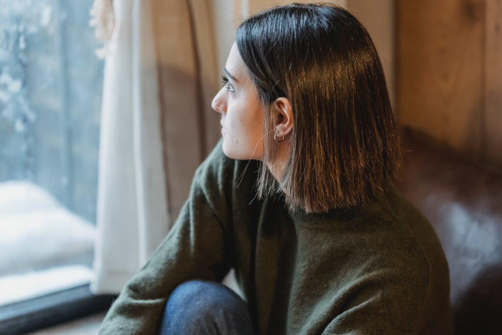 Jonge vrouw staart uit het raam