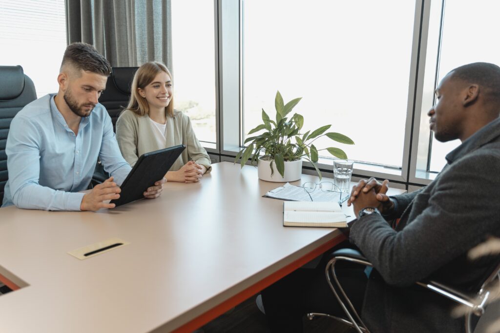 Vrouw aan tafel met twee mannen tijdens sollicitatiegesprek