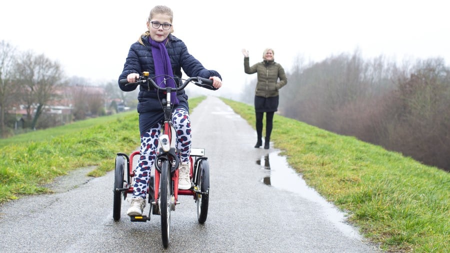 Meisje met bril op driewielfiets