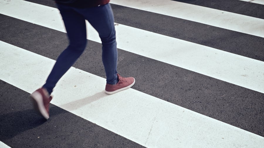 Jonge vrouw loopt over zebrapad