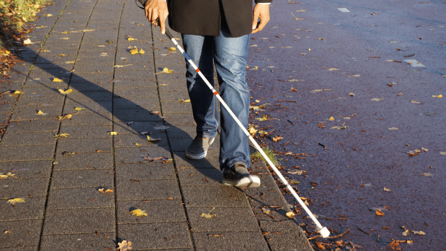 man met witte stok op trottoir