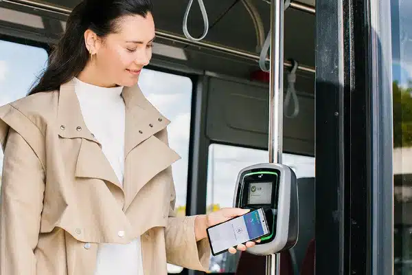 vrouw houdt smartphone tegen incheckpaal in de bus