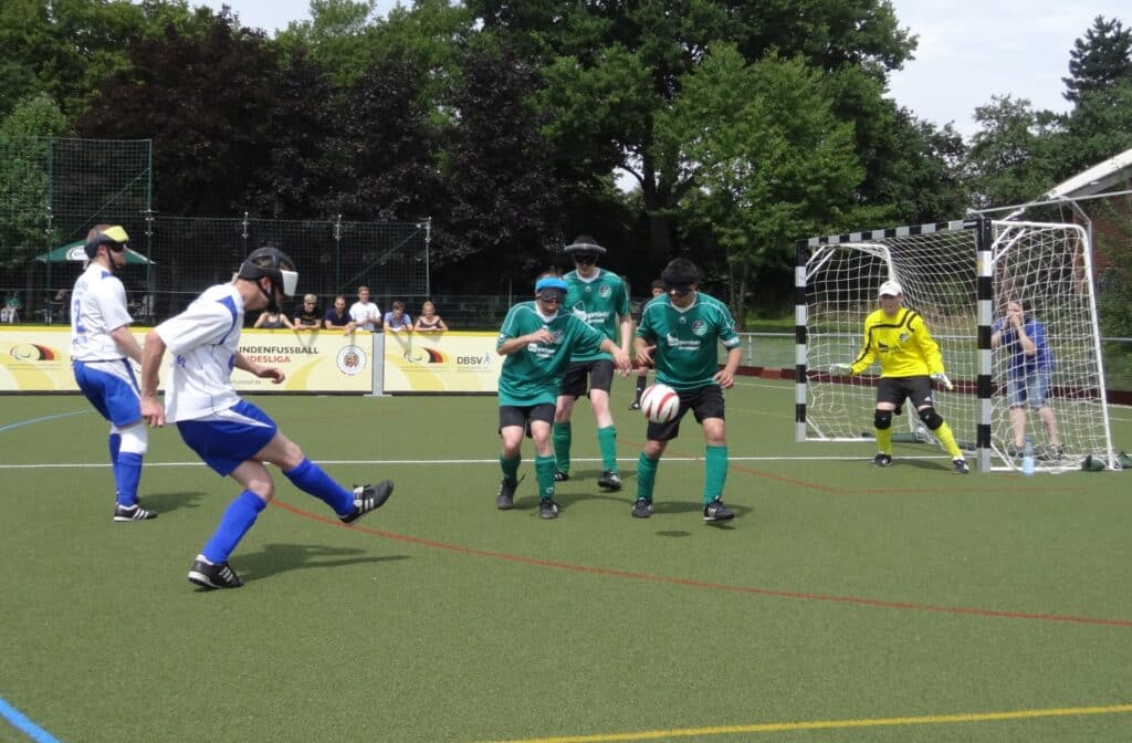 deelnemers spelen blind voetbal met kappen voor hun ogen