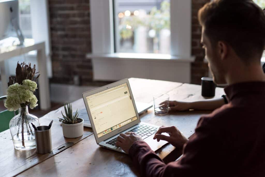 man zit achter een laptop aan een hoge tafel in een openbare ruimte