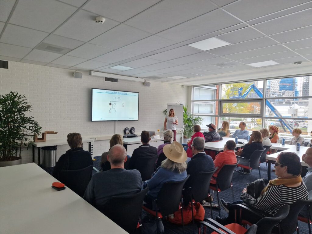 een volle zaal met mensen luistert aandachtig naar tijdens een van de workshops