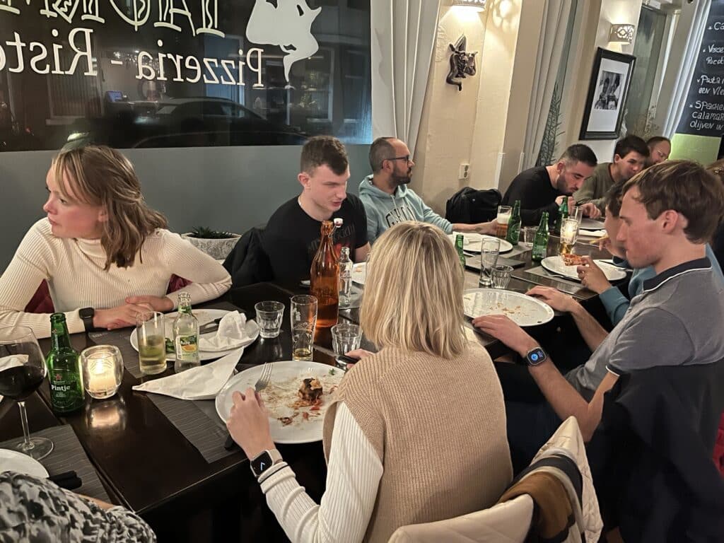 een lange tafel vol met jongeren geniet van een pizza