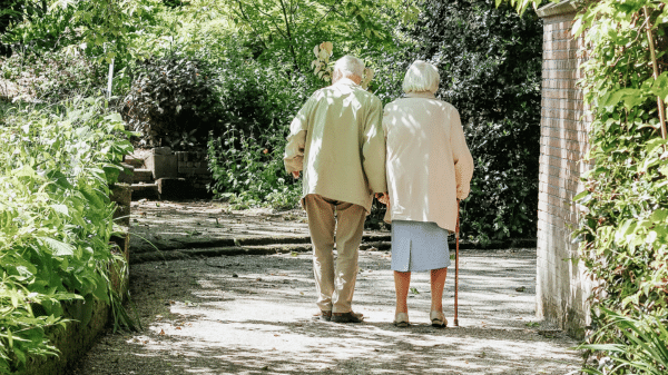 een seniore man en vrouw wandelt over een grindpad in een parkje