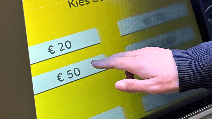 een vinger drukt op een geldmaat touchscreen om 50 euro op te nemen