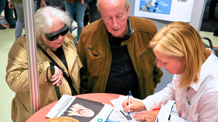 een man en vrouw in gesprek met een medewerkster van de oogvereniging op de ziezo beurs 2022