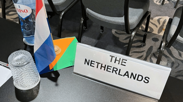 een kleine nederlandse vlag op een tafel in de zaal van de EBU, met een bordje waarop staat 'the netherlands' en een flesje water