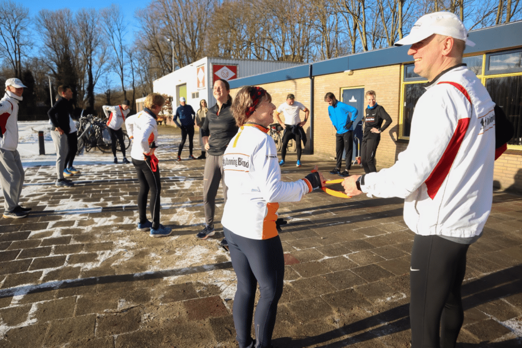 verschillende hartlopers rekken en strekken voor de harlooptraining. een man en zijn buddy houden samen een koortje vast, zodat ze een goede afstand van elkaar bewaren