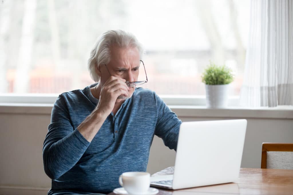 man met bril probeert de tekst op zijn laptopscherm te lezen