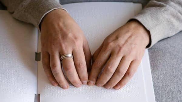 Twee handen rusten op een brailleboek