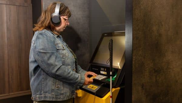Een vrouw maakt met koptelefoon gebruik van een pinautomaat