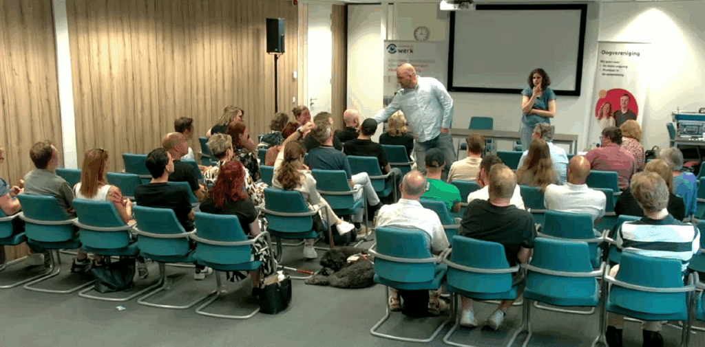 een zaal vol werkzoekenden en enkele werkgevers op 13 juni 2025 in Zwolle, er wordt een vraag gesteld vanuit het publiek, de presentator rijkt de microfoon uit.