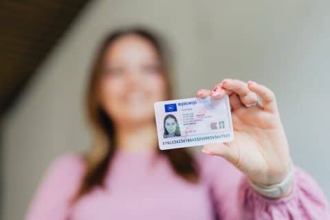 Een vrouw houdt haar rijwbewijs omhoog