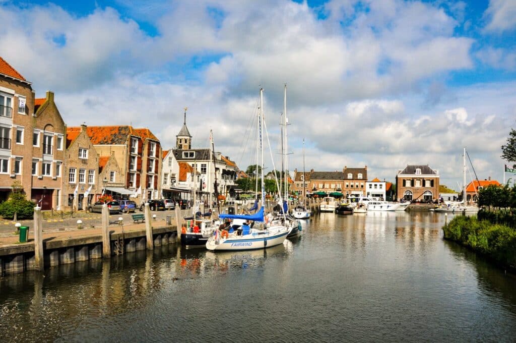decoratieve afbeelding van een gracht in Willemstad die vollicht met zeilboten, de zon schijnt