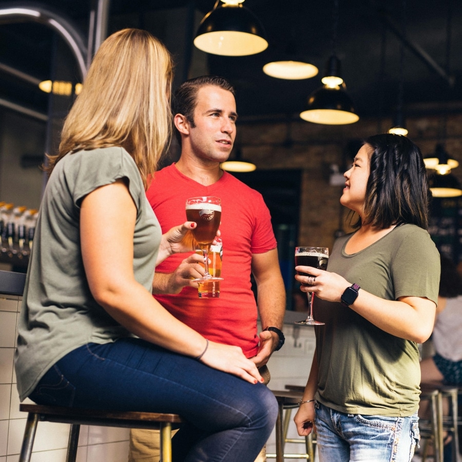 Drie jongeren zijn in een café aan de praat met een drankje in hun hand