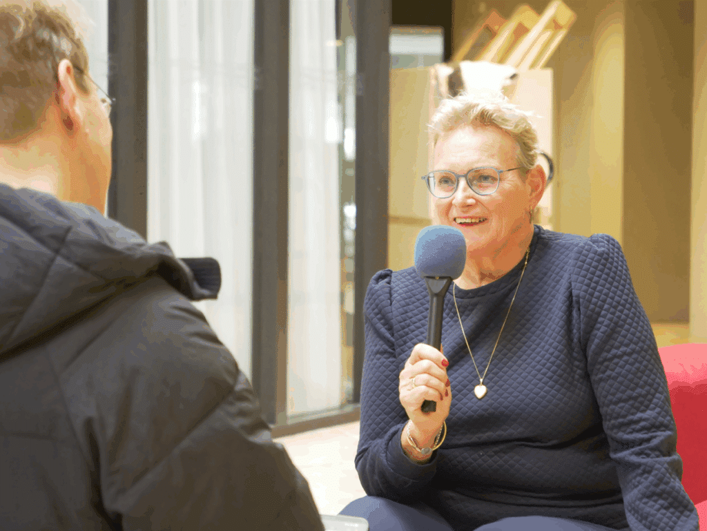 wethouder en loco-burgemeester Liesbeth Vos-Van de Weg houdt een microfoon vast, ze wordt geïnterviewd voor de podcast