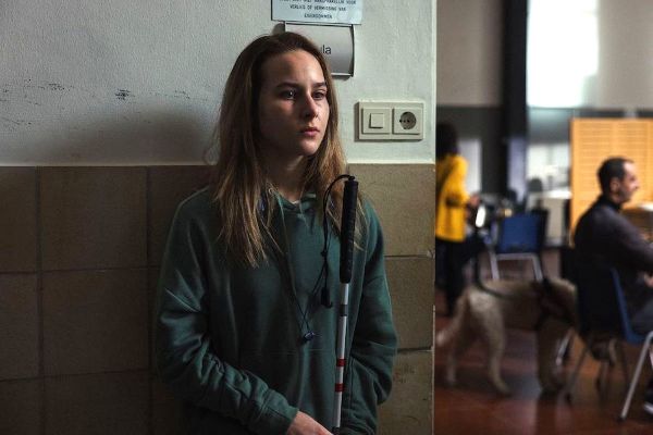 Hoofdpersoon Lot staat in het revalidatiecentrum met een taststok in haar hand