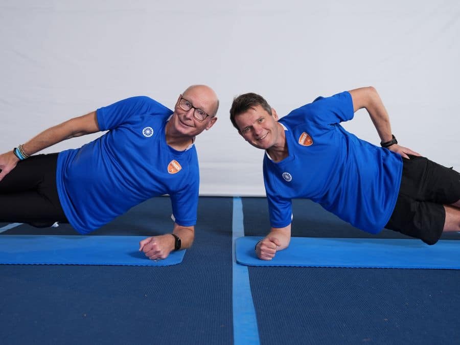 Twee mannen doen een sportoefening op een matje