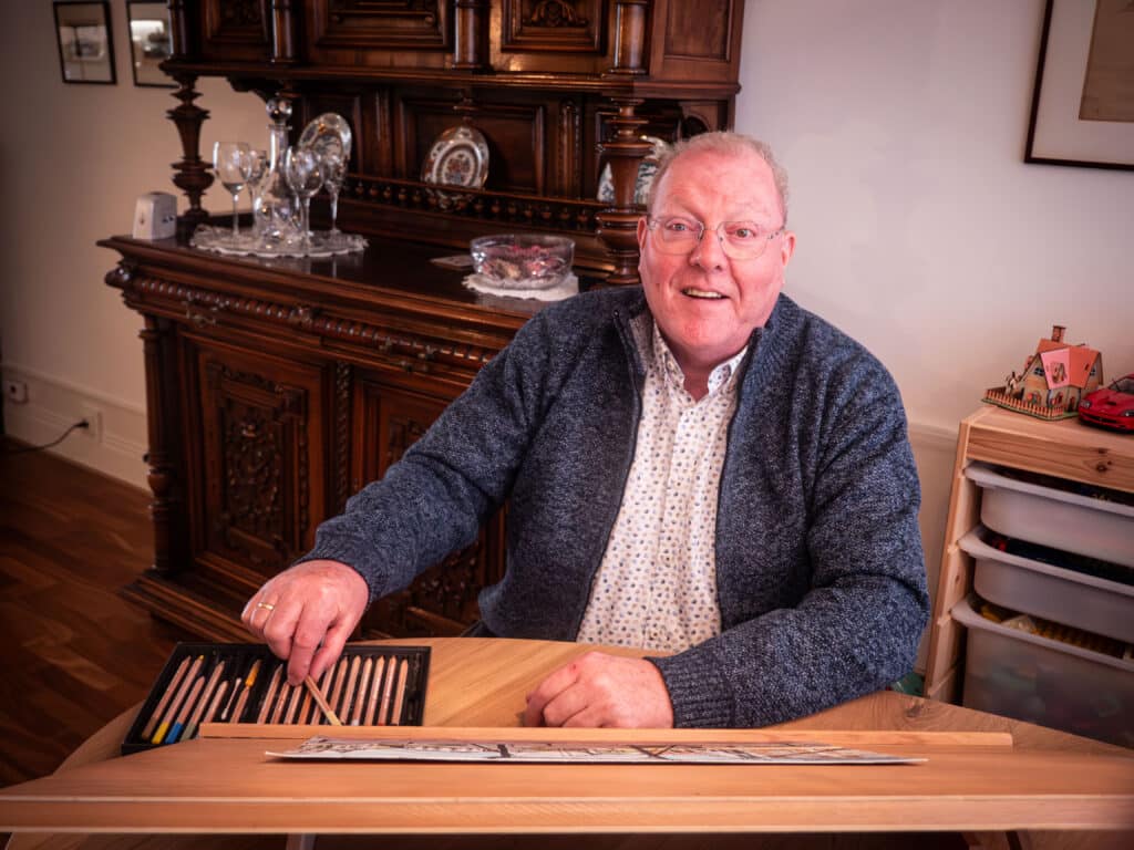 Dirk van Rij kijkt op van zijn tekentafel in de woonkamer