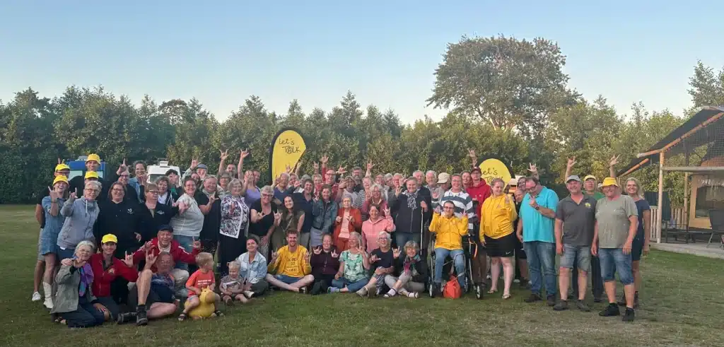 groepsfoto van zo'n 50 deelnemers van een activiteit, ze maken het "i love you" handgebaar